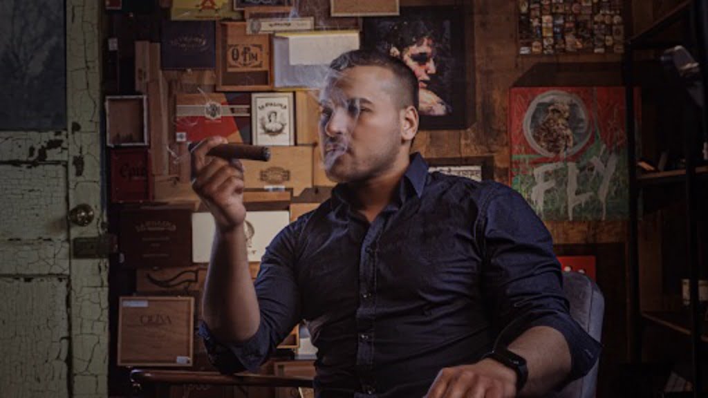 A man looking at a lit cigar